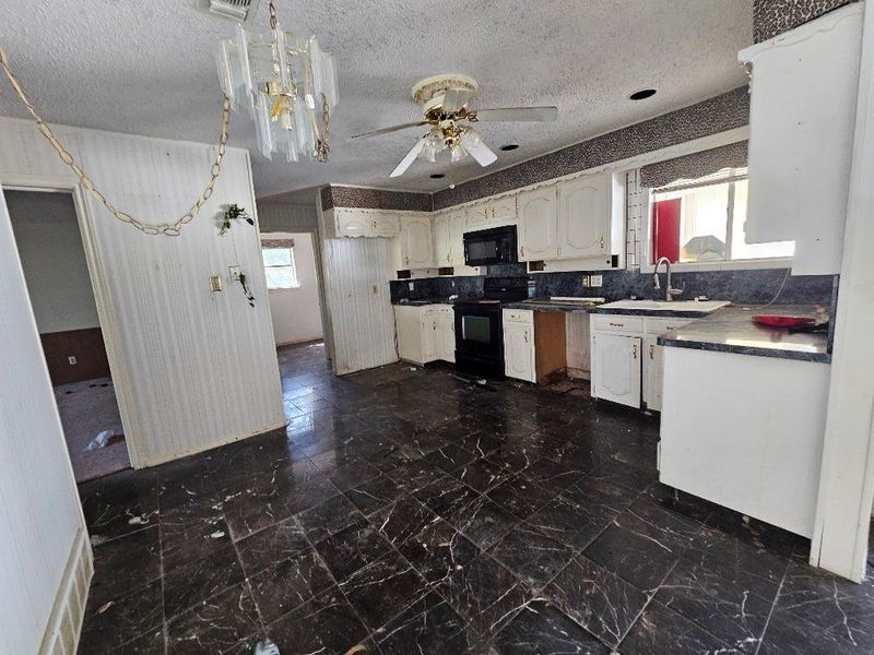 Kitchen with white cabinetry, dark countertops, black appliances, a textured ceiling, and ceiling fan Kitchen with white cabinetry, dark countertops, black appliances, a textured ceiling, and ceiling fan