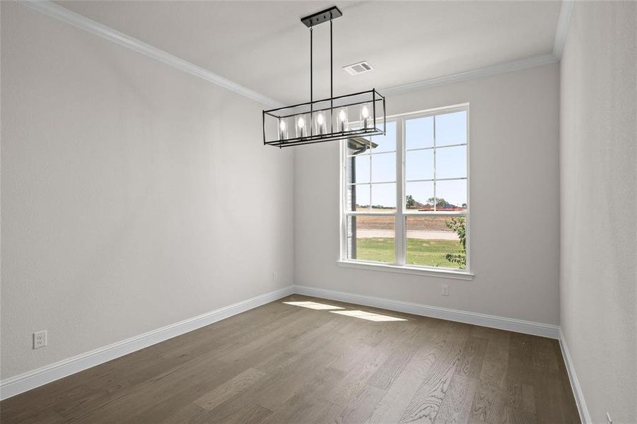 Unfurnished dining area featuring wood-type flooring, crown molding, and a chandelier