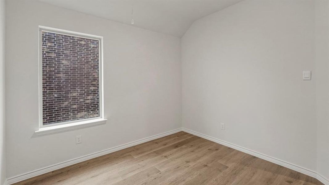 Room featuring wood-finish flooring, crisp white walls, and a large window with white trim