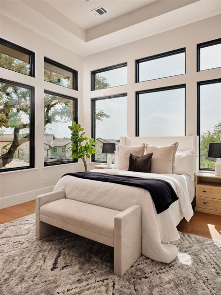 Natural light floods this spacious primary bedroom through multiple large windows, creating an airy and open ambiance. Natural light floods this spacious primary bedroom through multiple large windows, creating an airy and open ambiance.