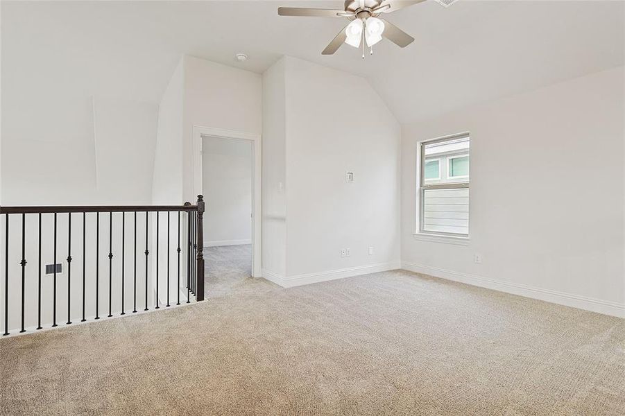 Carpeted empty room with ceiling fan and lofted ceiling