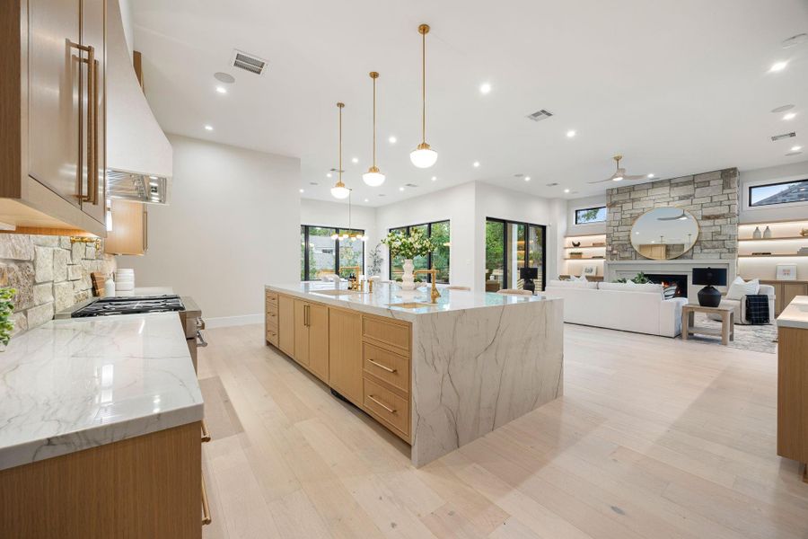 This expansive view highlights the heart of the home, where the kitchen seamlessly opens to the living space. The oversized island provides generous prep and seating space, while natural light pours in through large windows. The standout feature is the effortless indoor-outdoor connection, creating a bright, airy atmosphere that enhances both everyday living and entertaining.