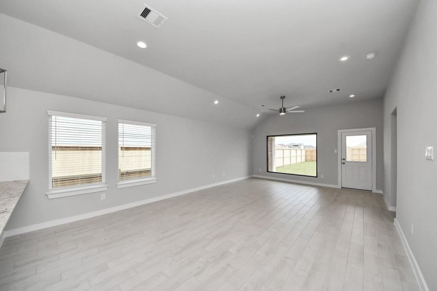 Welcome family and guests to your charming living room! With its high ceilings, recessed lighting, ceiling fan, custom paint, beautiful flooring, and large windows that let in abundant natural light, this room is perfect for gatherings. Sample photo of completed home with similar floor plan. Actual colors and selections may vary.