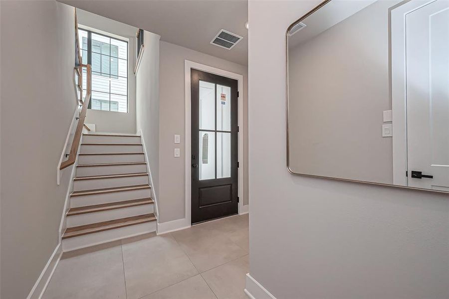 This inviting living room boasts light wood flooring, a sleek fireplace, and abundant natural light through large windows and glass doors, complemented by a stylish ceiling fan.