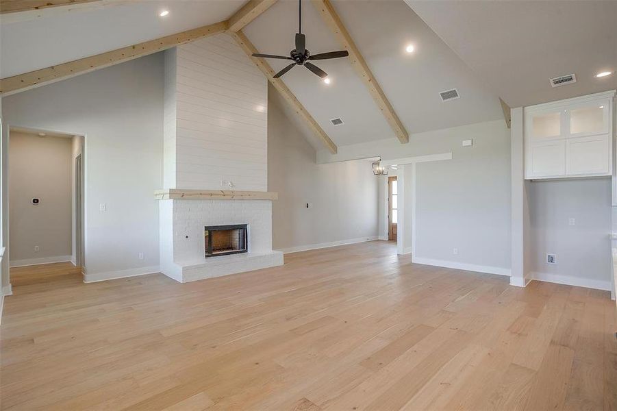 Unfurnished living room with visible vents, light wood-style flooring, a ceiling fan, and a brick fireplace Unfurnished living room with visible vents, light wood-style flooring, a ceiling fan, and a brick fireplace