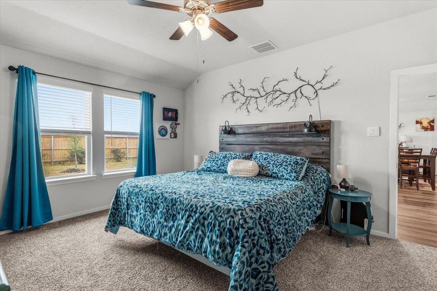 Bedroom featuring carpet flooring, vaulted ceiling, and a ceiling fan