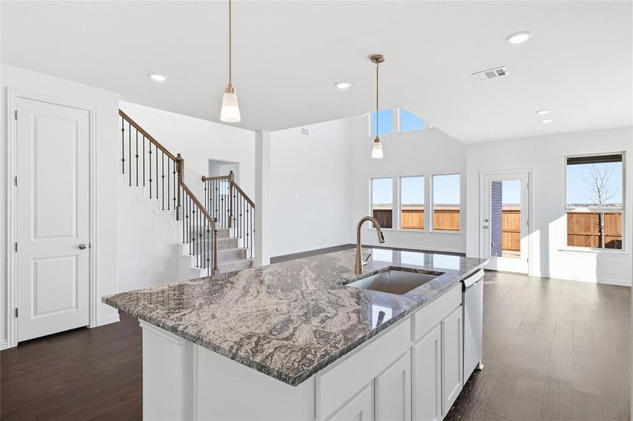 Kitchen island featuring a single-basin sink, brushed nickel faucet, and a patterned stone countertop