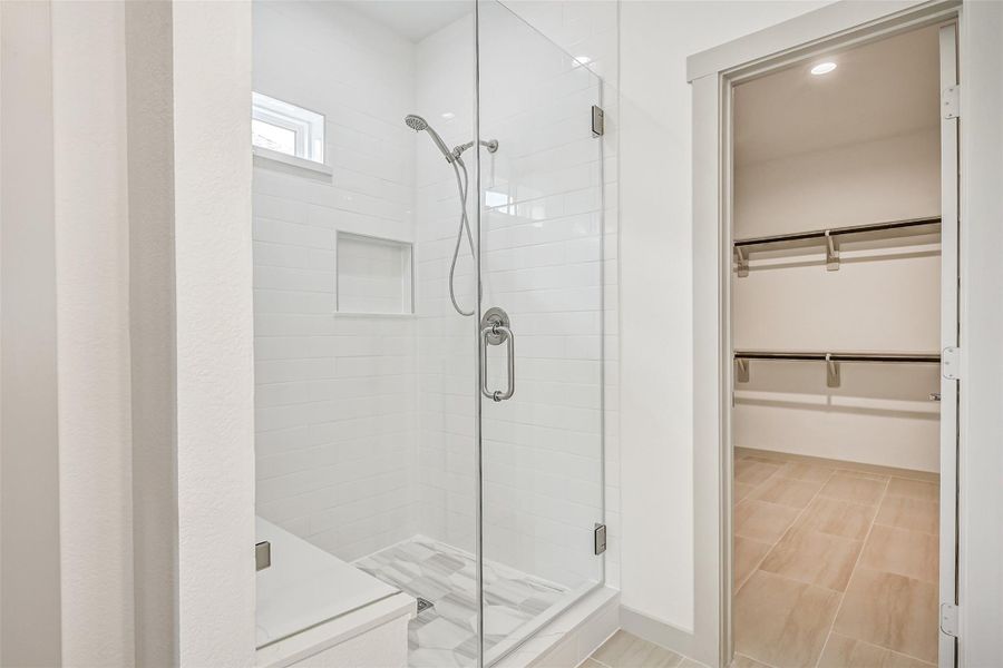 An oversized frameless glass shower showcases crisp tile surrounds, a built-in niche, handheld showerhead and natural light, creating a clean contemporary focal point in the primary bath. An oversized frameless glass shower showcases crisp tile surrounds, a built-in niche, handheld showerhead and natural light, creating a clean contemporary focal point in the primary bath.