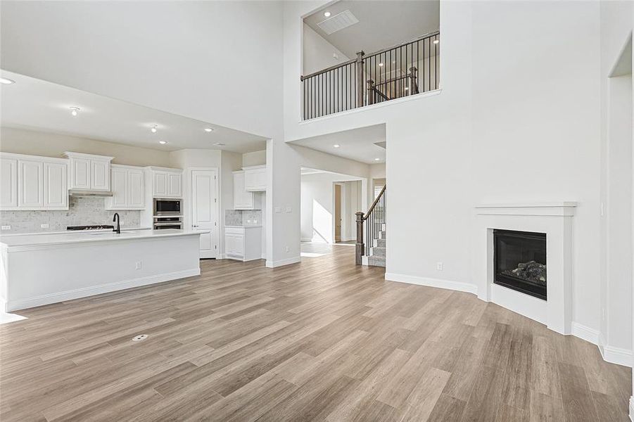 Unfurnished living room with a towering ceiling and light wood-type flooring