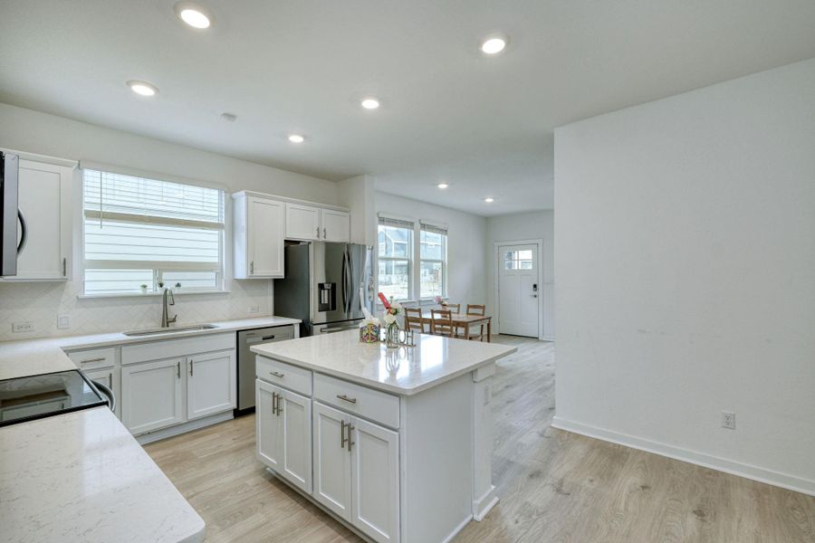 Kitchen featuring appliances with stainless steel finishes, a sink, backsplash, and light wood finished floors