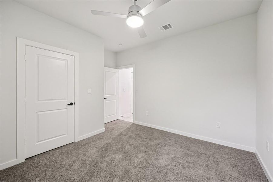 Unfurnished bedroom with carpet and a ceiling fan Unfurnished bedroom with carpet and a ceiling fan