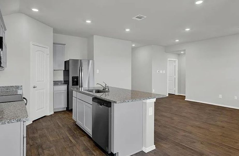 Open-concept kitchen featuring an island with a sink and dishwasher, granite countertops, stainless steel appliances, recessed lighting, and wood-finish flooring Open-concept kitchen featuring an island with a sink and dishwasher, granite countertops, stainless steel appliances, recessed lighting, and wood-finish flooring