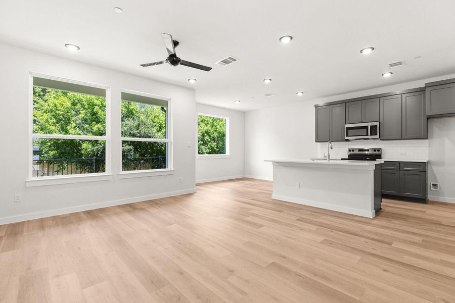 A well-lit, open-concept living area with a contemporary kitchen and views of vibrant greenery.