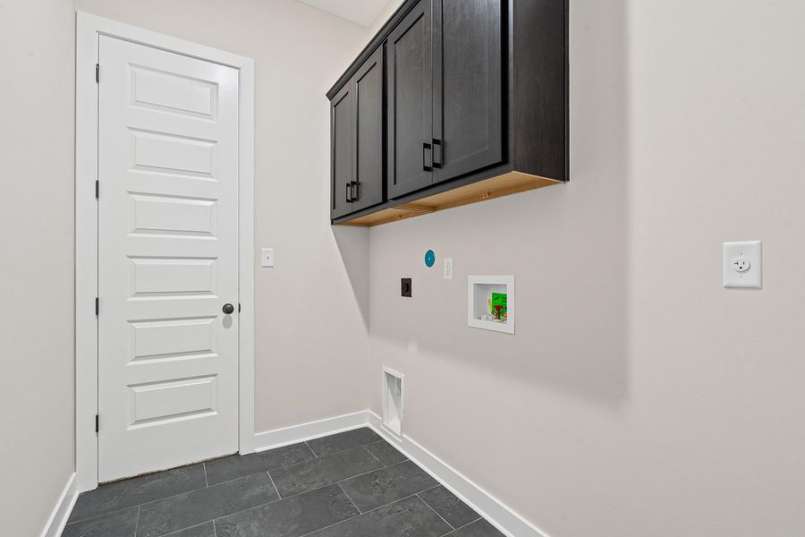 Laundry area with cabinet space, washer hookup, hookup for an electric dryer, and dark tile patterned floors