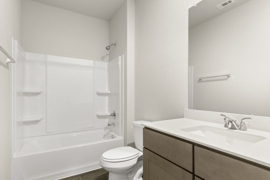 Image of a bathroom with a white shower ILO tub, a white vanity with a mirror and brown cabinets