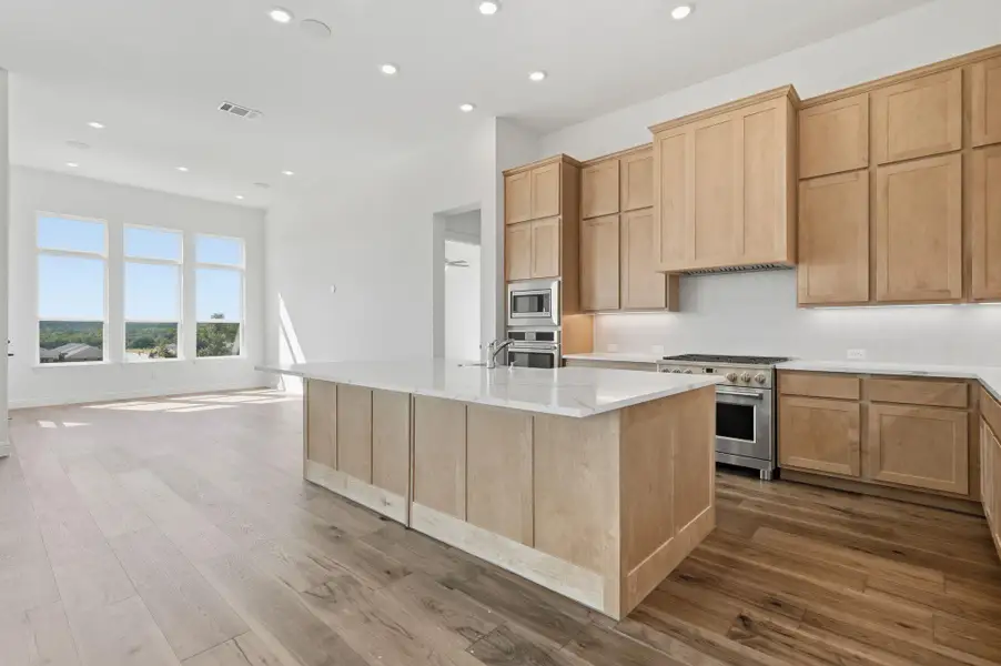 Kitchen featuring light brown cabinets, appliances with stainless steel finishes, dark wood-style floors, and recessed lighting