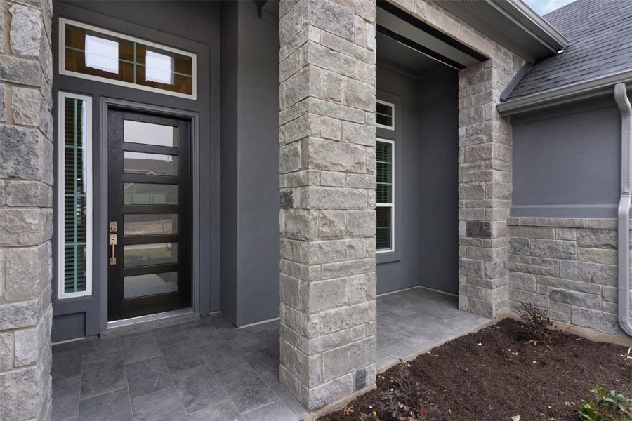 View of exterior entry featuring stone siding, stucco siding, and roof with shingles