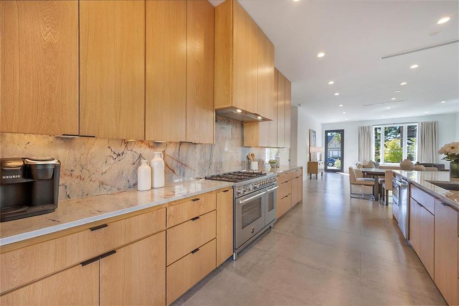 Kitchen featuring tasteful backsplash, appliances with stainless steel finishes, extractor fan, and light brown cabinets