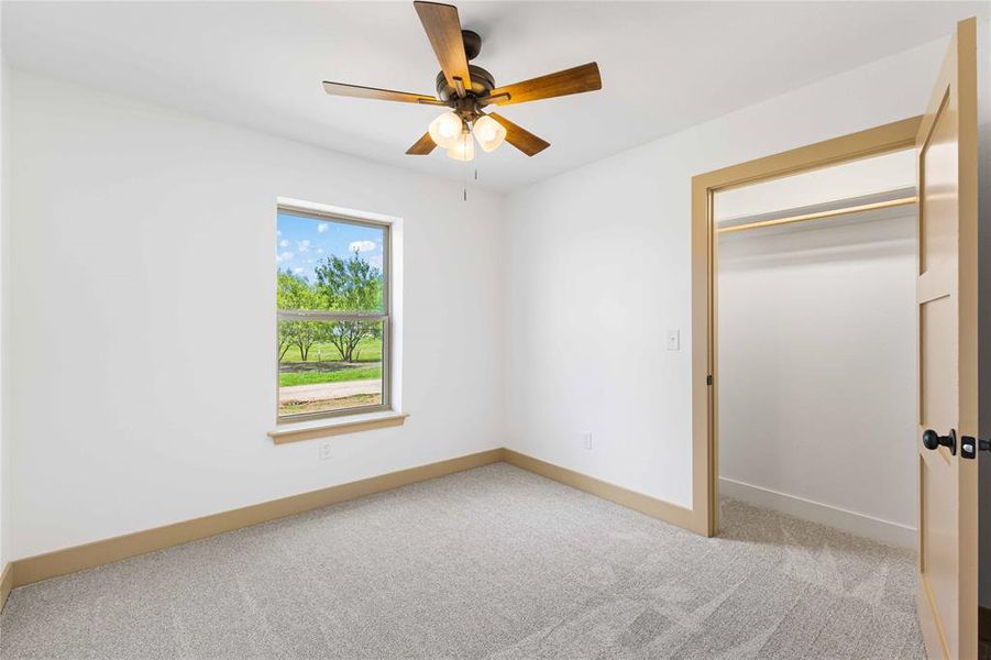 Unfurnished bedroom featuring light carpet, ceiling fan, and a closet