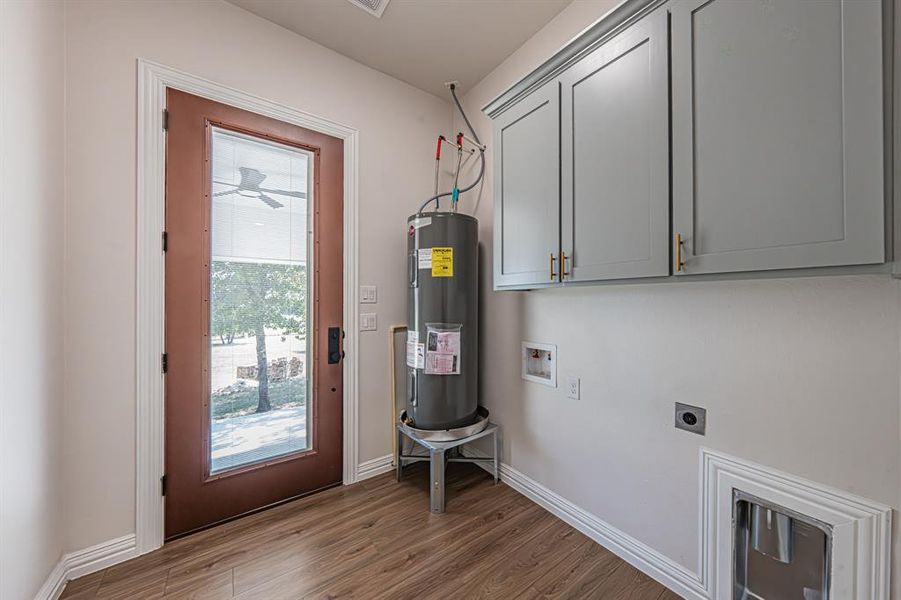 Washroom featuring dark wood-style floors, cabinet space, electric water heater, electric dryer hookup, and hookup for a washing machine Washroom featuring dark wood-style floors, cabinet space, electric water heater, electric dryer hookup, and hookup for a washing machine