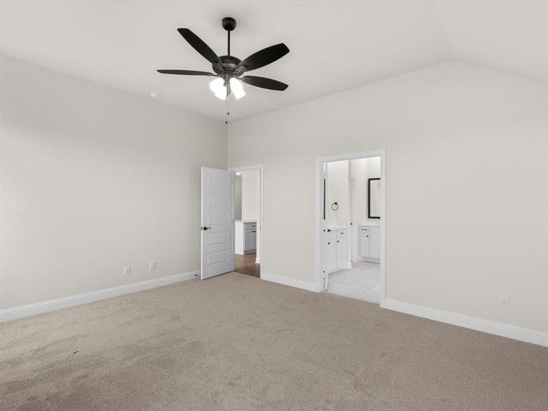 Unfurnished bedroom with light carpet, a ceiling fan, ensuite bathroom, and vaulted ceiling