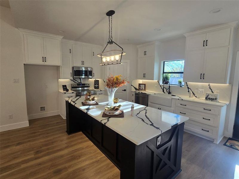 Kitchen featuring white cabinetry, decorative light fixtures, stainless steel appliances, a center island, and dark wood-style flooring