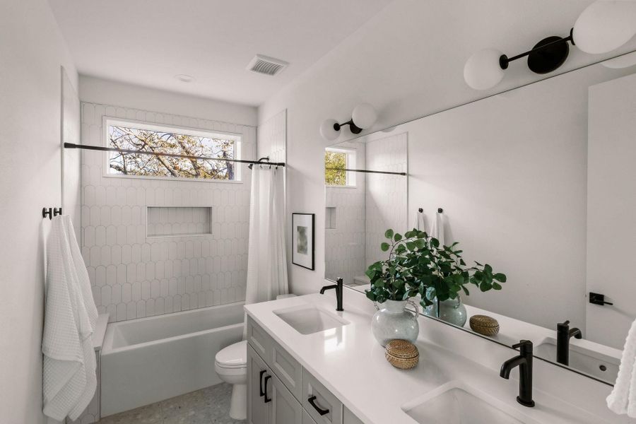 Full bathroom with double vanity, shower / bath combo, and healthy amount of natural light Full bathroom with double vanity, shower / bath combo, and healthy amount of natural light