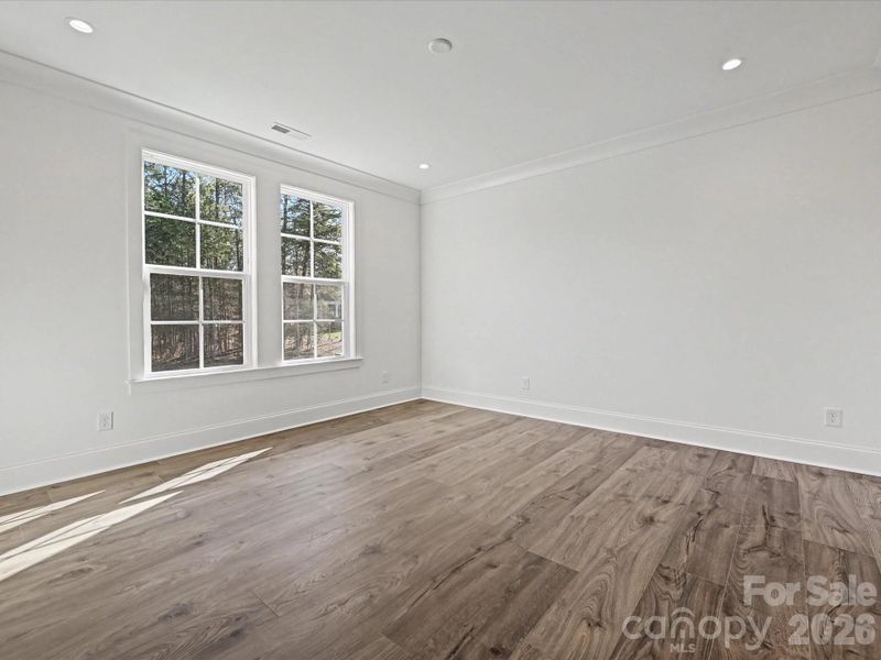 Light-filled secondary bedroom with large windows, neutral finishes, and ample space for guests, family, or a home office.