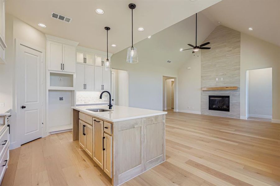 Kitchen with high vaulted ceiling, open floor plan, a kitchen island with sink, light wood finished floors, and pendant lighting Kitchen with high vaulted ceiling, open floor plan, a kitchen island with sink, light wood finished floors, and pendant lighting