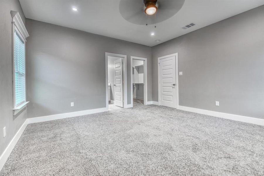 Unfurnished bedroom with a spacious closet, light colored carpet, connected bathroom, ceiling fan, and recessed lighting