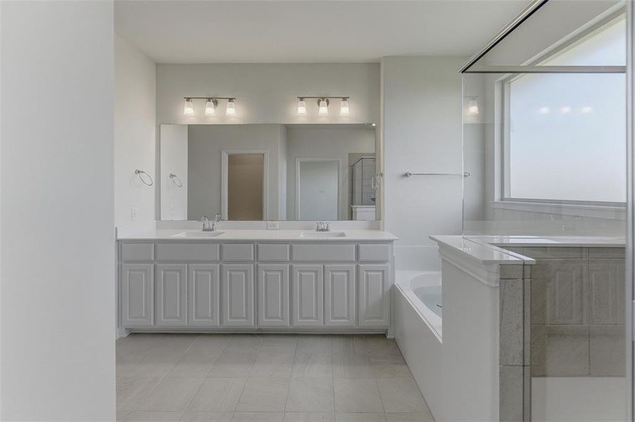 Bathroom featuring a double vanity with ample cabinetry, dual undermount sinks, and a substantial mirror Bathroom featuring a double vanity with ample cabinetry, dual undermount sinks, and a substantial mirror