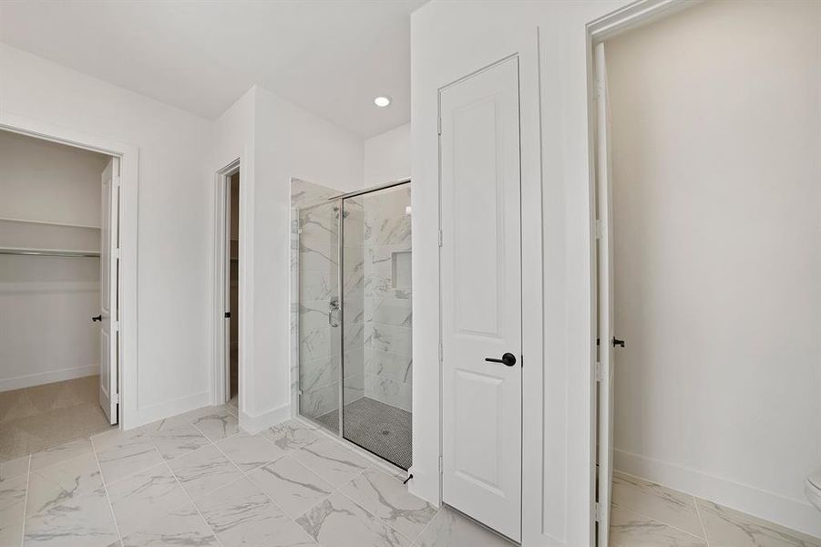 Full bathroom with a marble finish shower, light marble finish flooring, a spacious closet, and recessed lighting Full bathroom with a marble finish shower, light marble finish flooring, a spacious closet, and recessed lighting