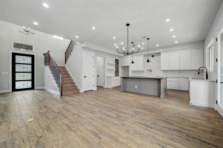 Kitchen with a sink, light wood finished floors, and an inviting chandelier