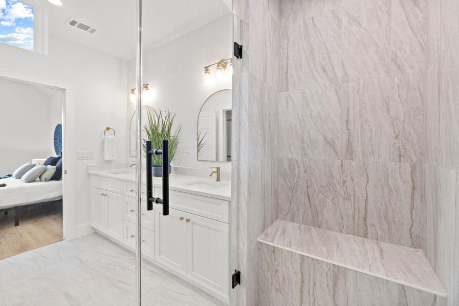 Bathroom with double vanity, connected bathroom, and light marble finish flooring