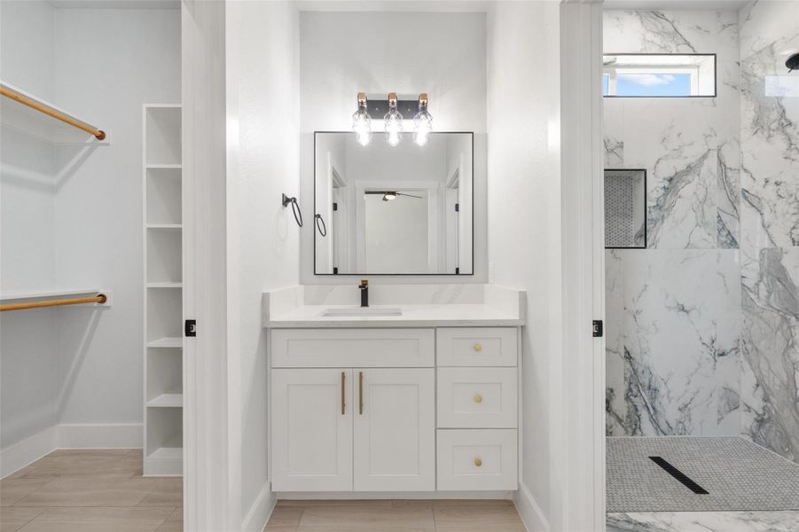Full bathroom with vanity, a marble finish shower, and a walk in closet