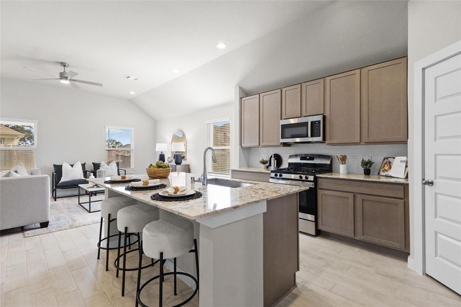 Open-concept kitchen features a large granite-topped island with seating, stainless steel appliances, ample cabinetry, and seamless connection to the living area. Open-concept kitchen features a large granite-topped island with seating, stainless steel appliances, ample cabinetry, and seamless connection to the living area.