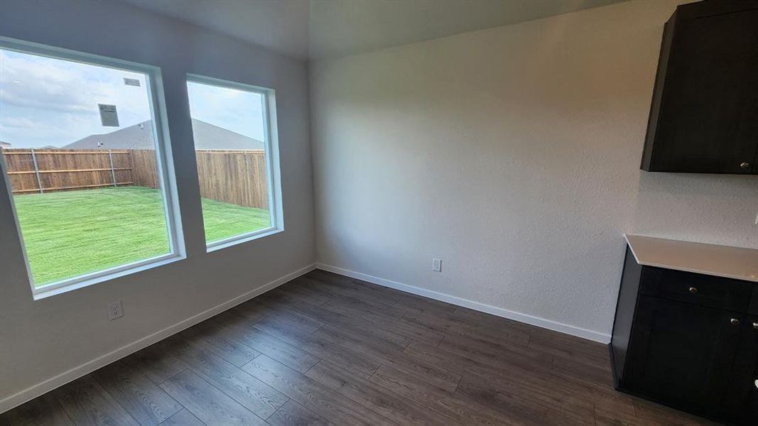Room featuring wood-finish flooring, two large windows, white baseboards, and a neutral wall color Room featuring wood-finish flooring, two large windows, white baseboards, and a neutral wall color
