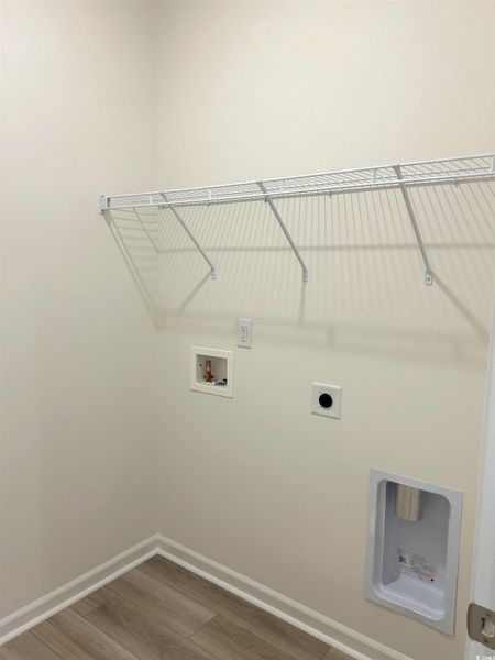 Washroom with electric dryer hookup, wood finished floors, and washer hookup