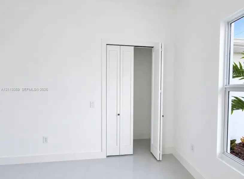 Neutral-toned tile flooring, white-finished walls, and a multi-panel bifold closet door