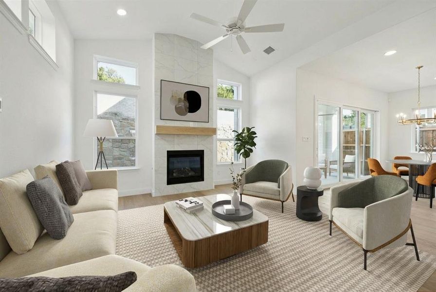 Living area with vaulted ceiling, light wood-type flooring, hanging lights, a tiled fireplace, and ceiling fan Living area with vaulted ceiling, light wood-type flooring, hanging lights, a tiled fireplace, and ceiling fan