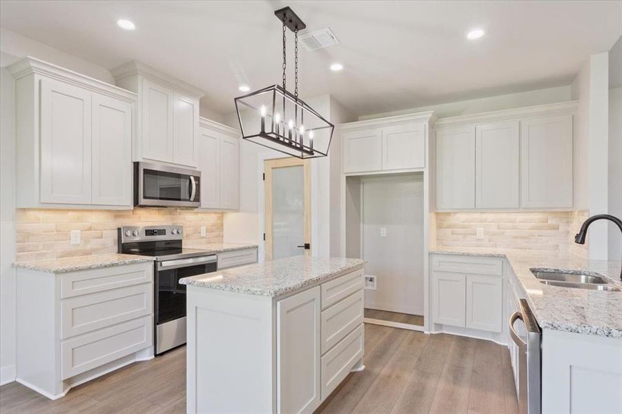 Kitchen featuring decorative backsplash, appliances with stainless steel finishes, white cabinetry, light stone countertops, and recessed lighting Kitchen featuring decorative backsplash, appliances with stainless steel finishes, white cabinetry, light stone countertops, and recessed lighting