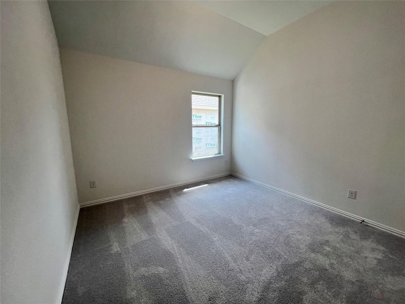 Carpeted empty room with lofted ceiling and baseboards Carpeted empty room with lofted ceiling and baseboards