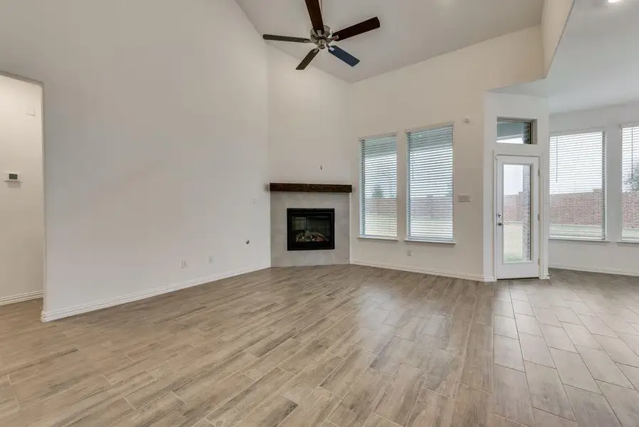 Unfurnished living room with a towering ceiling, light hardwood / wood-style flooring, and ceiling fan