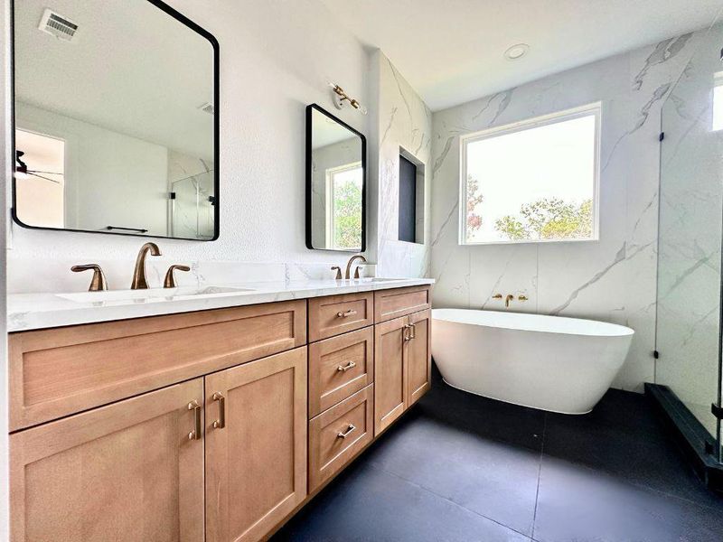 A well-appointed primary bathroom showcases dual vanities, a free-standing tub, and ample natural light. A well-appointed primary bathroom showcases dual vanities, a free-standing tub, and ample natural light.