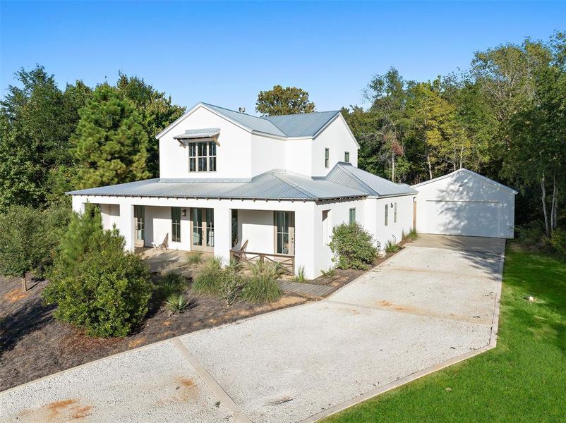 Modern farmhouse featuring covered porch, an outbuilding, and a garage Modern farmhouse featuring covered porch, an outbuilding, and a garage
