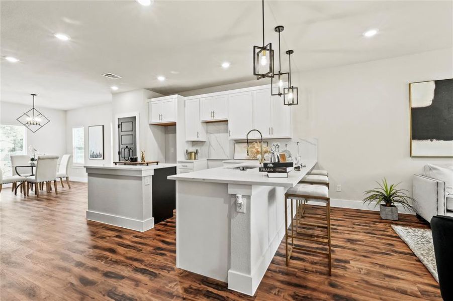 Kitchen featuring white cabinets, pendant lighting, a breakfast bar area, recessed lighting, and a chandelier Kitchen featuring white cabinets, pendant lighting, a breakfast bar area, recessed lighting, and a chandelier