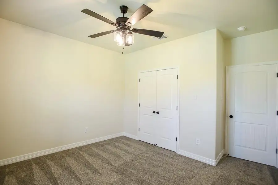Unfurnished bedroom featuring carpet flooring, a closet, and a ceiling fan Unfurnished bedroom featuring carpet flooring, a closet, and a ceiling fan