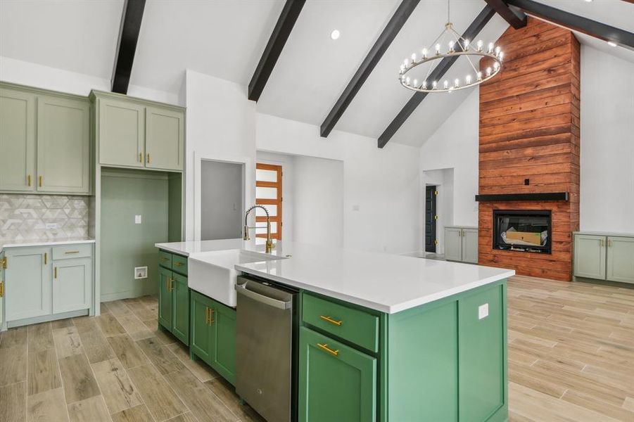 Kitchen with green cabinetry, a kitchen island with sink, beam ceiling, wood tiled floors, and backsplash Kitchen with green cabinetry, a kitchen island with sink, beam ceiling, wood tiled floors, and backsplash