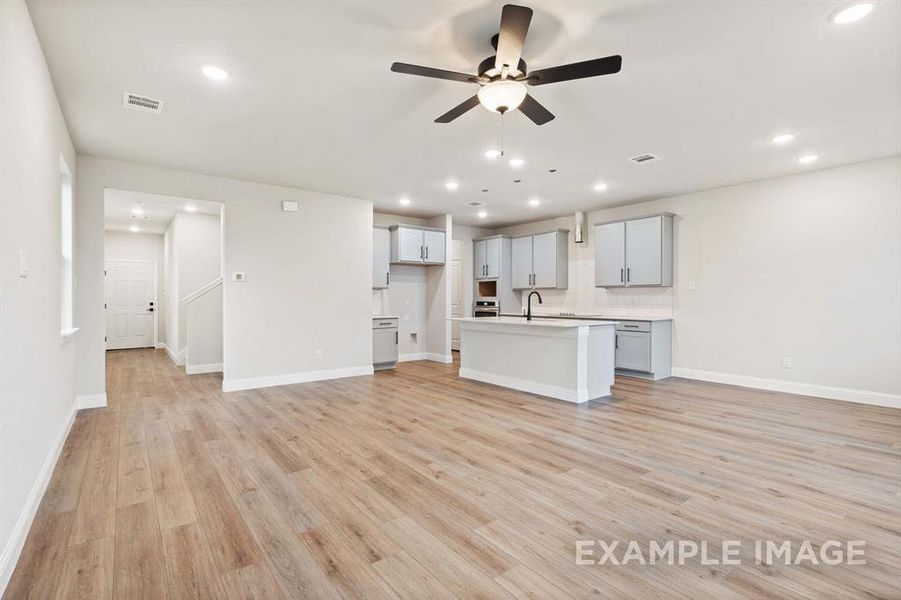 Unfurnished living room with ceiling fan, sink, and light hardwood / wood-style floors