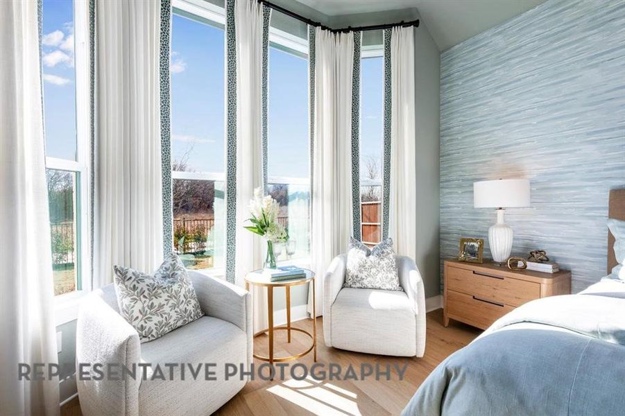 Bedroom with wood finished floors and wallpapered walls